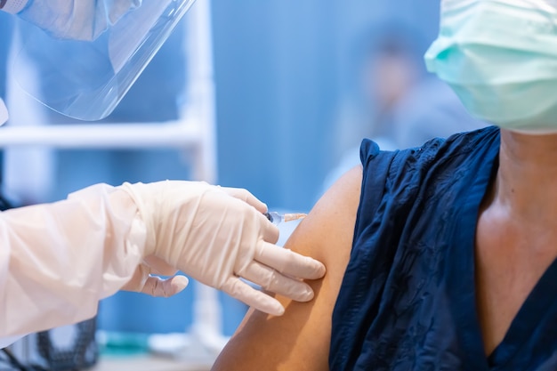 Photo closeup covid-19 vaccine injecting into patient arm shoulder with single use plastic syringe by doctor, boost the immune system with inactivated or adenovirus virus