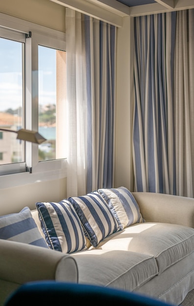 Closeup of cozy upholstered sofa in beige color with decorative pillows in vertical bluebeige