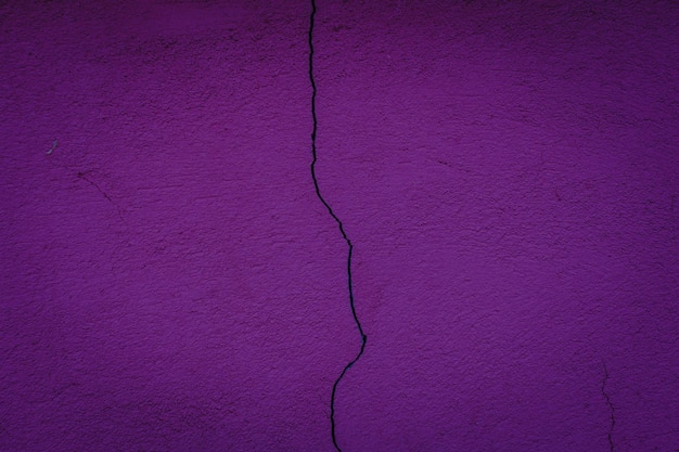 Closeup of a crack in a purple concrete wall