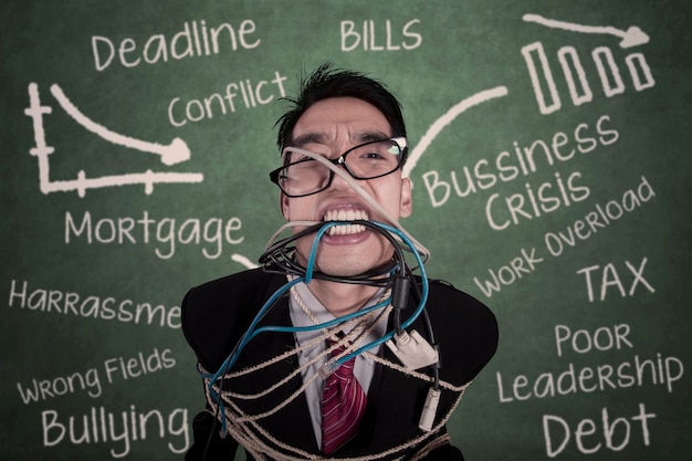 Closeup crazy businessman tied in cable and rope at class