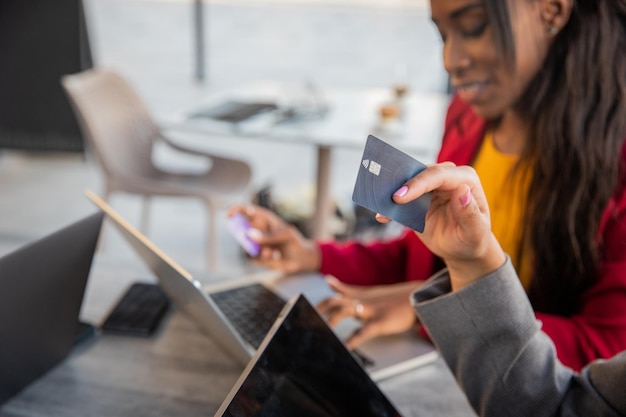 Closeup of a credit card held by a woman shopping online with her friend photo with copy space