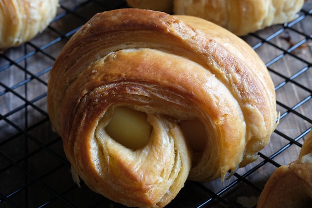 Foto primo piano di croissant su una griglia di raffreddamento. pasta frolla a forma di mezzaluna. ripieno di formaggio, cioccolato, prosciutto