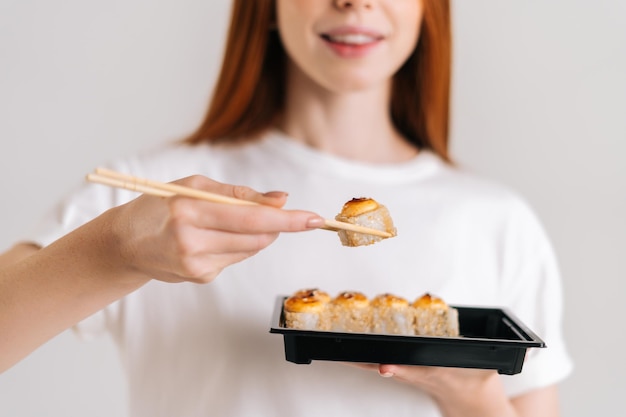 맛있는 스시 롤을 먹는 인식할 수 없는 웃는 젊은 여성의 근접 촬영 자른 얼굴