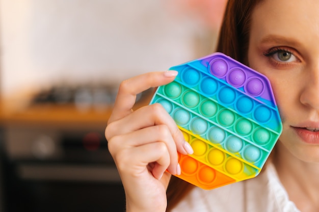 Closeup cropped shot of redhead young woman holding in hand near face colorful iridescent soft