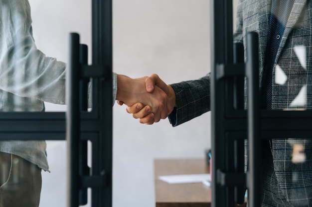 Closeup cropped shot of unrecognizable business partners shaking hands agree to deal at office Two businessmen handshaking after successful project