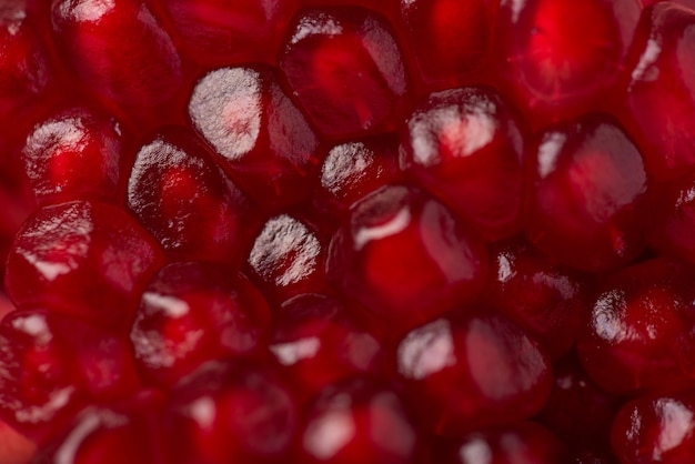 Closeup cropped view macro photo of red juicy fresh pomegranate seeds texture