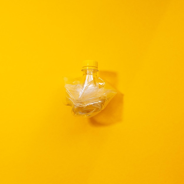 Closeup of crumpled plastic bottle isolated on yellow background