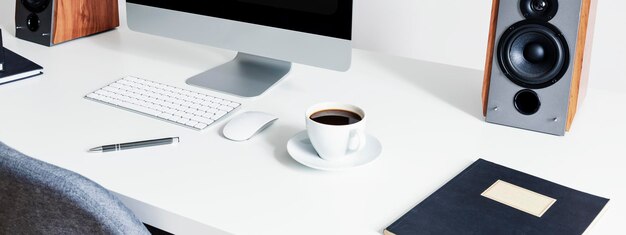 Closeup on a cup of coffee next to a computer mouse and keyboard on white desk in an interior for a freelancer Real photo