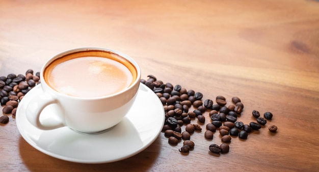 Closeup of a cup of latte with golden foam and  blend coffee beans on an old wooden  background