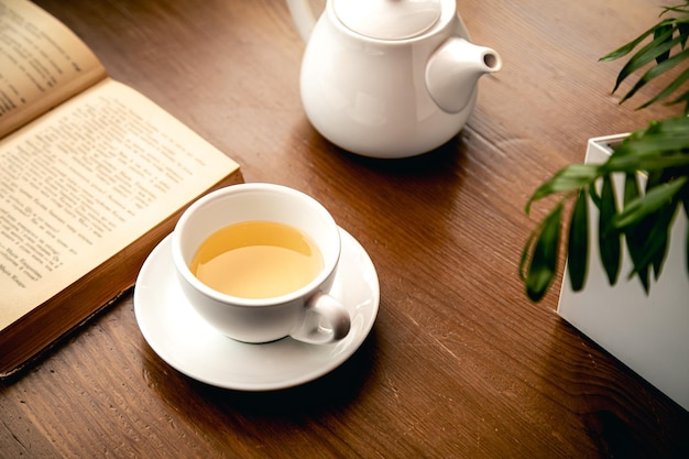 Closeup a cup of tea and a book on a wooden table