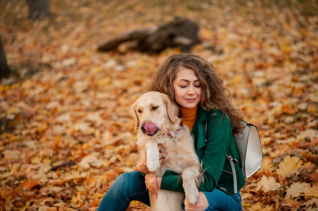 春の季節に彼女の犬と抱きしめる巻き毛の女性のクローズアップ