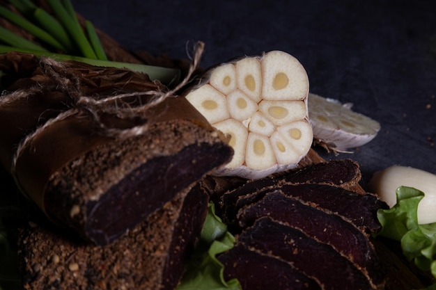 Foto primo piano di un taglio di aglio che giace accanto alla carne su un piatto di legno
