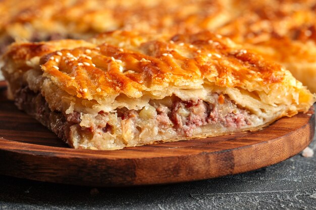 Closeup on cut pie with beef and potatoes filling on the wooden table