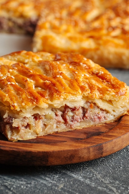 Closeup on cut pie with beef and potatoes filling on the wooden table