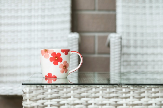 Photo closeup cute cup on blurred wood weave table and chair textured background