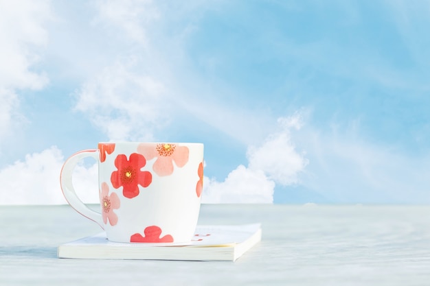 Closeup cute cup white book on desk with beautiful blue sky background