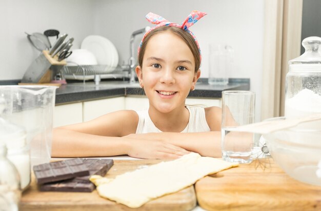 Крупным планом милая улыбающаяся девушка, опираясь на деревянную кухонную доску на кухне