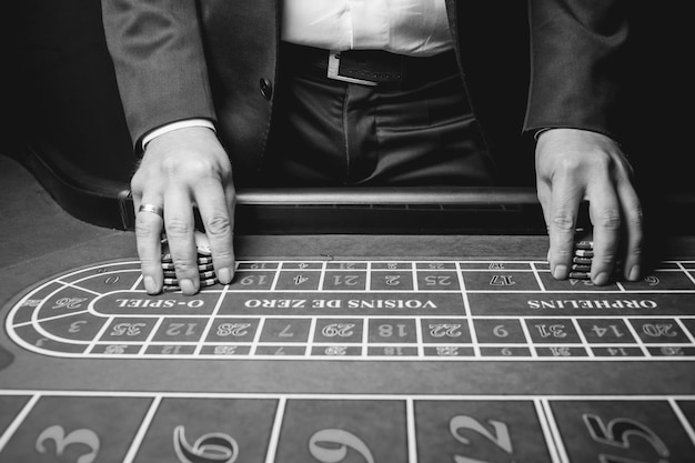 Foto primo piano del rivenditore con fiches foto in bianco e nero il croupier del casinò detiene fiches