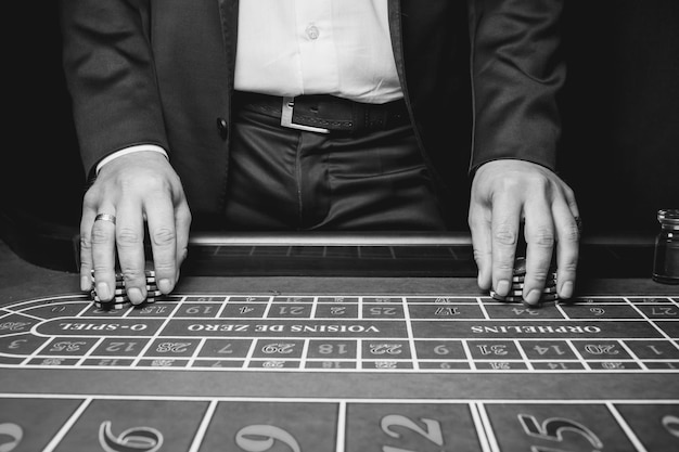 Foto primo piano del rivenditore con fiches foto in bianco e nero il croupier del casinò detiene fiches