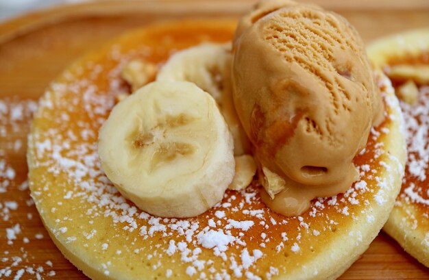 Closeup of delectable pancake topped with fresh banana and caramel ice cream