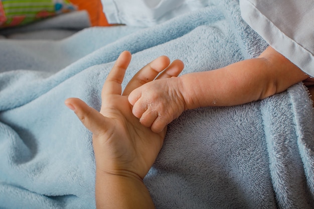 彼の母親の手のひらに生まれたばかりの赤ちゃんの繊細な手のクローズアップ