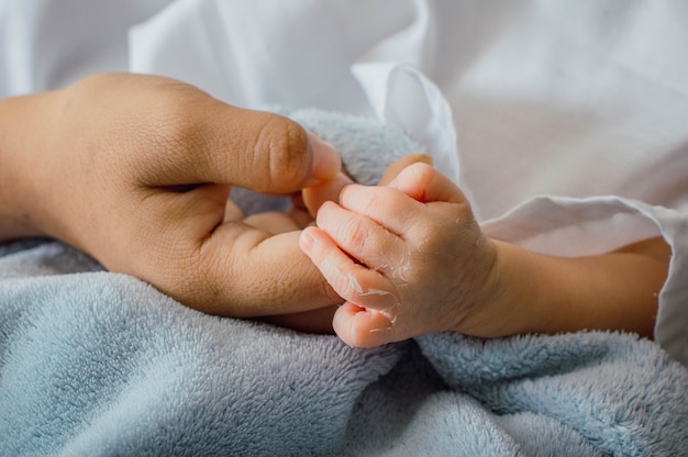 closeup of delicate hands of newborn baby in the palm of his mother