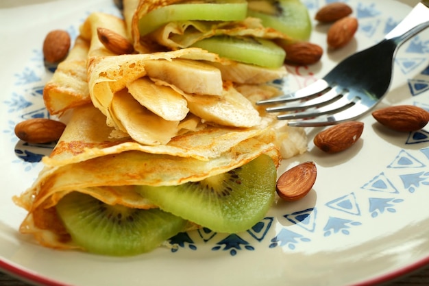 Closeup of delicious pancakes with banana and kiwi on plate