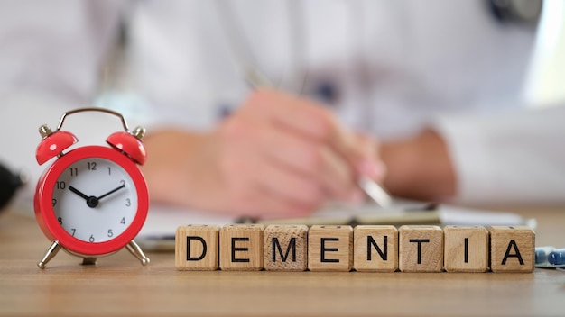 Photo closeup of dementia word collected of wooden cubes in row and alarm clock decrease in cognitive