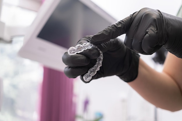 Foto primo piano della mano del dentista che tiene un trattamento allineatore dentale invisibile bei denti