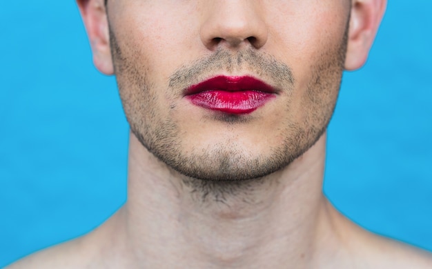 Foto dettaglio del primo piano di un uomo con rossetto su una parete blu