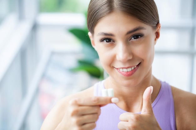 Dettaglio del primo piano della donna che mette la gomma da masticare rosa nella sua bocca