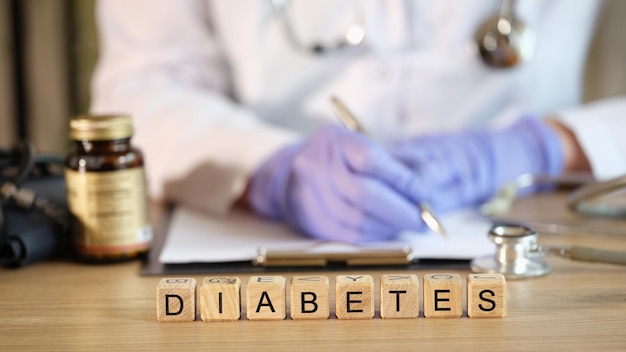 Photo closeup of diabetes word collected with wooden blocks in row female endocrinologist writing