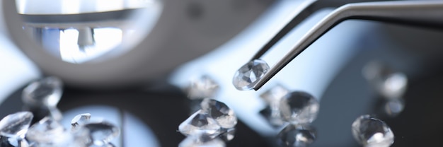 Photo closeup of diamond stone in metal tweezers. jewelry repair shop concept