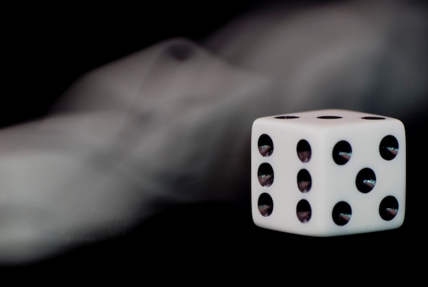 Closeup of a dice with the smoke on a black background