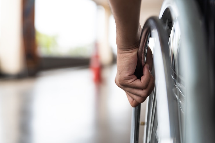 Photo closeup disabled man hand on wheel of wheelchair.