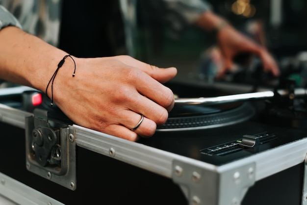 Closeup of DJ mixing vinyl records on turntable at street music festival in evening Selective focus on disjockey's hand