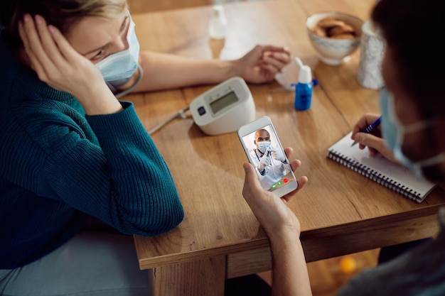 Closeup of doctor advising his patients via video call while they are measuring blood pressure at home