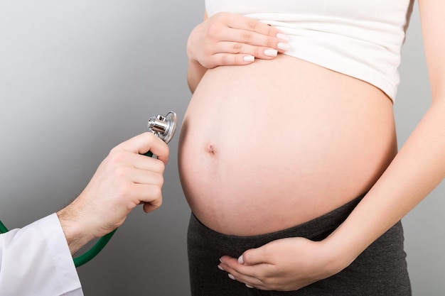 Closeup of doctor examining pregnant woman on colourful background