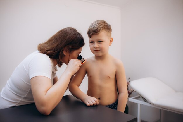 Photo closeup of doctor examining skin of child patient with dermatoscope