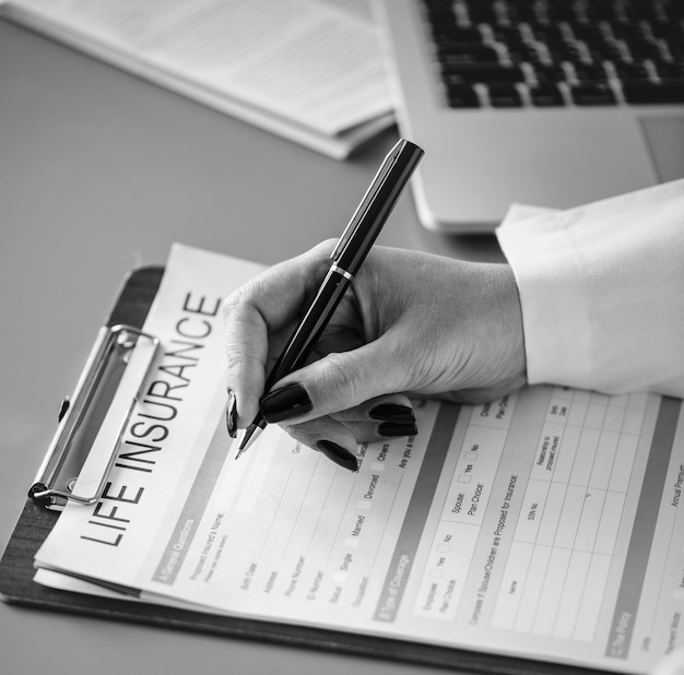 Closeup of doctor filling life insurance form