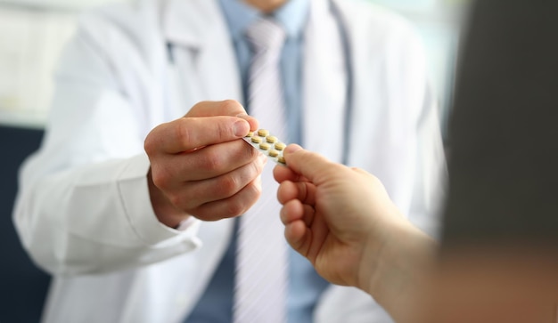 Closeup of doctor hand giving medical pills to patient