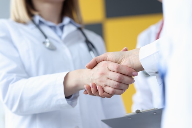 Closeup of doctor and patient handshake in clinic. Council of doctors concept