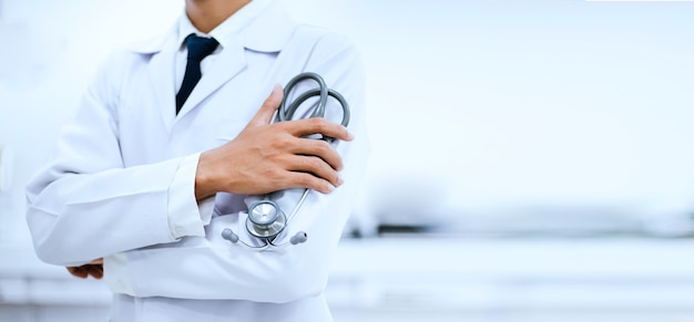 Foto primo piano della mano del medico che tiene uno stetoscopio con sfondo sfocato in ospedale