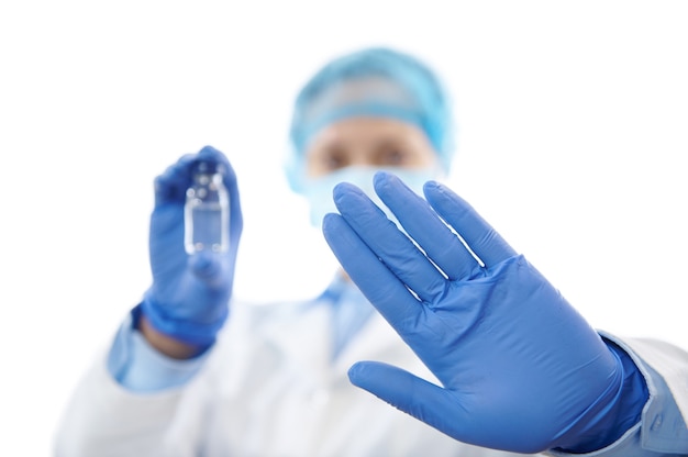 Foto primo piano della mano del medico in guanto medico protettivo che gesturing stop sullo sfondo di un medico in possesso di un vaccino isolato su sfondo bianco. lotta alle malattie infettive