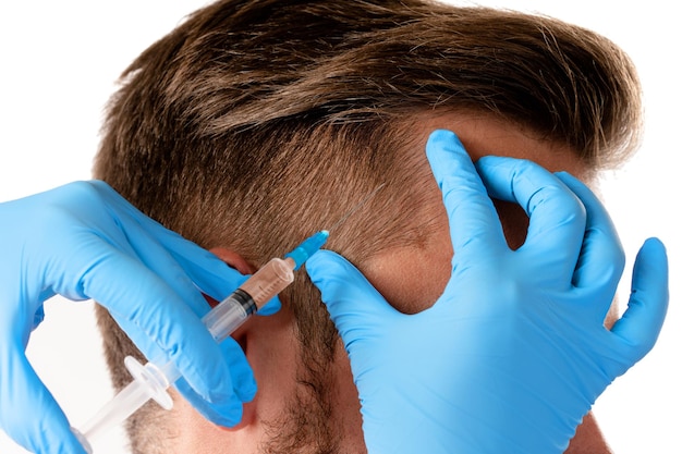 Closeup of doctor's hand with a syringe and man receiving scalp injection for hair grow