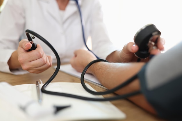 Photo closeup of doctors hand measuring blood pressure of male patient clinic or hospital office