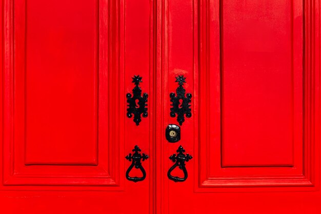 Closeup door with a bright red color with black metallic accessories and keyhole