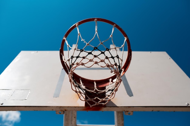 Closeup down view of basketball hoop on background of blue\
sky