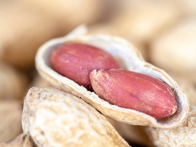 Closeup dried peanuts in shells on peanuts background on wooden table