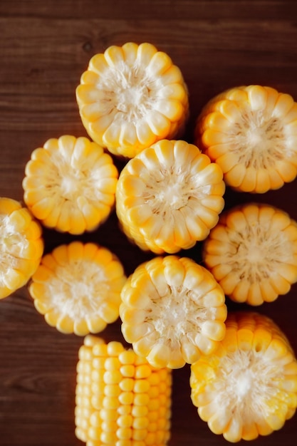 Photo closeup of ears of corn cut into pieces fresh corn on a wooden background top view